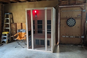 A room with a dartboard, a folding screen, and a ladder.