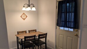 A dining area with a wooden table and chairs, a chandelier, a door with a window, and a wall-mounted sign. - Cozy GP Retreat, Sauna + King Size Bed (Grants Pass)