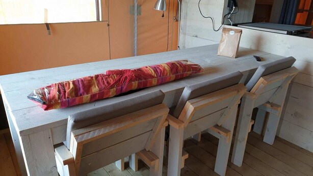 Una mesa de madera con bancos, un mantel estampado y una lámpara.