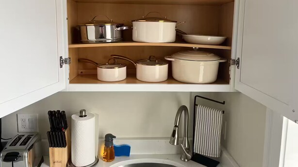 A kitchen with white cabinets, a toaster, a knife block, a paper towel holder, a soap dispenser, and a hanging towel rack.