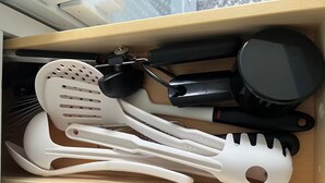 A kitchen drawer with various utensils and cookware.