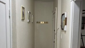 A hallway with white walls, a red patterned carpet, and a ceiling light.
