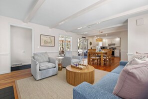 Ein Wohnzimmer mit gestreiften Sesseln, einem runden Couchtisch und einem blauen Sofa.
