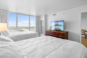A hotel room with two beds, a TV, and a view of the beach. - Cozy Water Views Apt Fort Myers (Fort Myers)