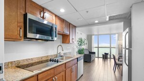 Eine moderne Küche mit Granit Arbeitsplatten, Edelstahlgeräten und Holzschränken, mit Blick auf das Meer.
