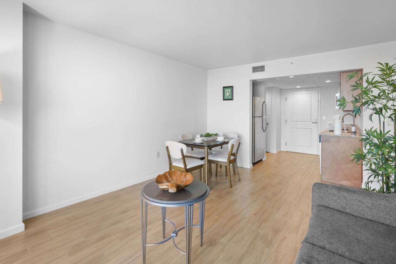 A modern apartment with a dining area, kitchen, and a grey sofa.