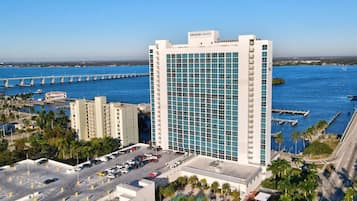 A high-rise hotel with a marina view, featuring a prominent 'EDISON GRAND' sign, multiple parking levels, and a rooftop pool area.