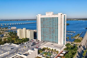 Ein Hochhaus-Hotel mit Blick auf eine Marina, mit einem gut sichtbaren 'EDISON GRAND'-Schild, mehreren Parkebenen und einem Poolbereich auf dem Dach.