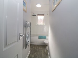 Ein schmales Badezimmer mit Dusche, Toilette und Handtuchhalter.
