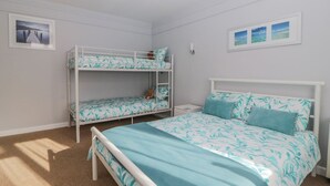 A bedroom with bunk beds, a single bed, and a nightstand. - Devon Seaside Apartment (Paignton)