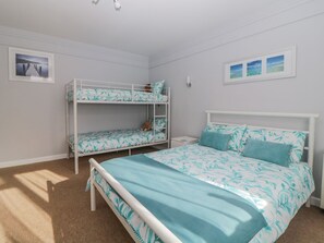 Ein Schlafzimmer mit Etagenbetten, einem Einzelbett und einem Nachttisch.