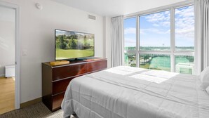 Et hotelværelse med en stor seng, et fjernsyn på en trækommode og udsigt til en golfbane gennem vinduet.