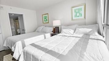 Een hotelkamer met twee bedden, een nachtkastje, een lamp en twee ingelijste foto’s aan de muur.