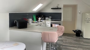 Eine kleine Küche mit Barbereich, einem Kühlschrank und einem Mülleimer.