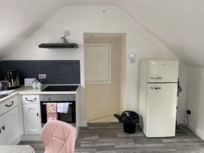 A compact kitchen with a built-in oven, a refrigerator, a coffee maker, and a small sink. - The Cottage (Middlesbrough)