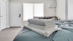 Een slaapkamer met een bed, een raam, een airconditioning en een deur.