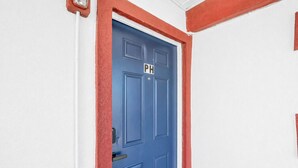 Una porta blu con il cartello PH, pareti bianche e finiture rosse.