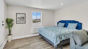 A bedroom with a bed, a window, a plant, and a radiator. - Penthouse Suite Steps to the Beach | Jersey Shore Stay (Seaside Heights)