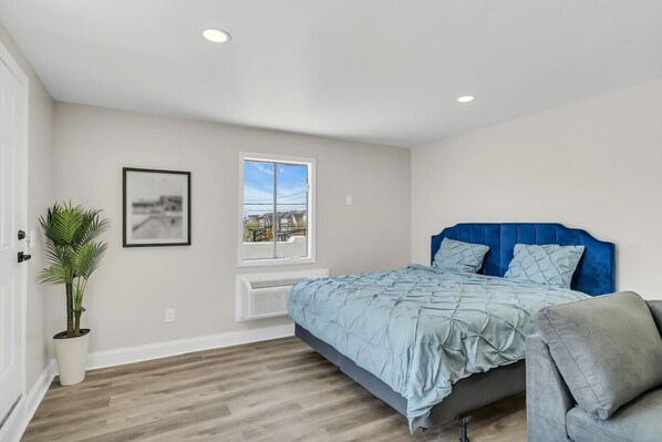 Un dormitorio con cama, ventana, planta y radiador.