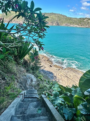 Una escalera que conduce a una zona costera con vistas al mar y vegetación.