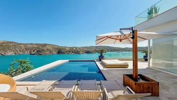 Zona de piscina con sillones de descanso y vista al mar.