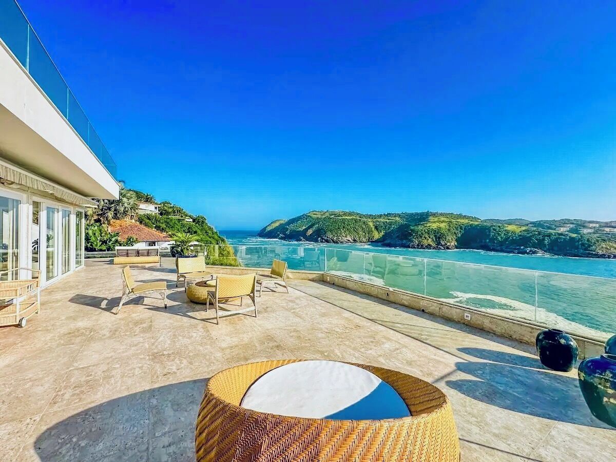 Una terraza con asientos al aire libre, vista al mar y un edificio con grandes ventanales.