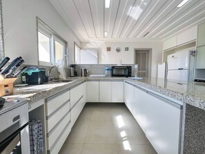 Una cocina moderna con armarios blancos, encimeras de granito, microondas y cafetera.