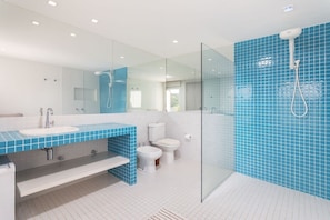 Un baño moderno con cabina de ducha de vidrio, lavabo blanco y bidé.