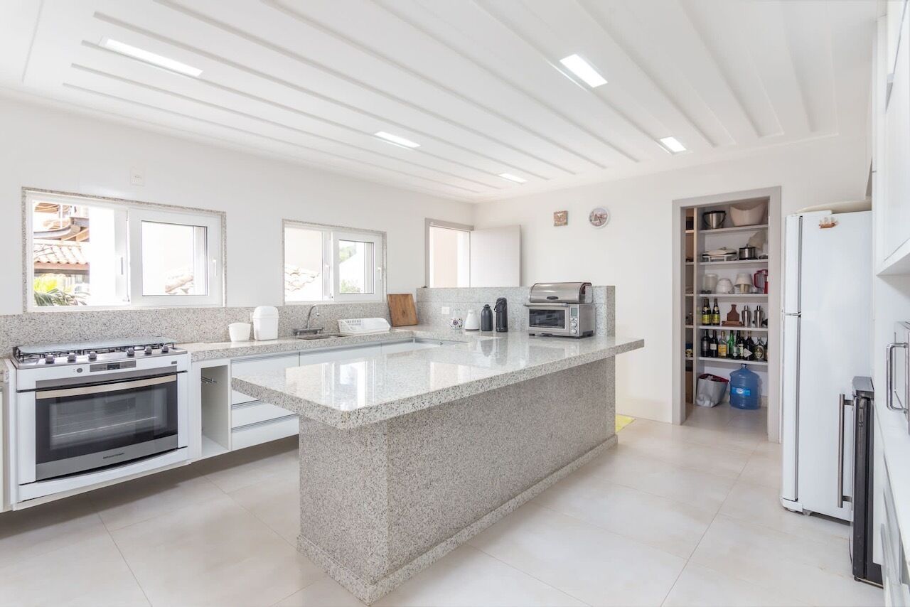 Cozinha moderna com ilha central, forno embutido, micro-ondas e geladeira.