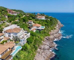 A coastal residential area with houses, a swimming pool, and a view of the ocean.