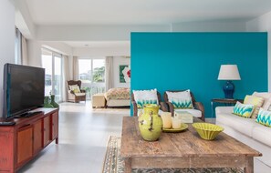 A living room with a television, a sofa, a coffee table, and a teal accent wall.