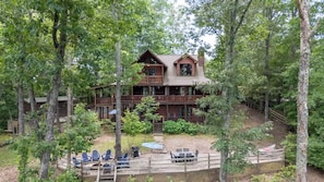 A cabin with a deck, surrounded by trees.