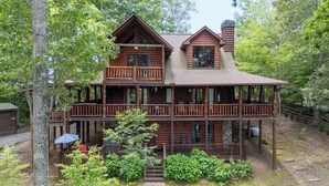 A two-story log cabin with a balcony, surrounded by trees. - Whippoorwill Calling - Endless Mountain Views, Hot Tub and Fire Pit (Mineral Bluff)