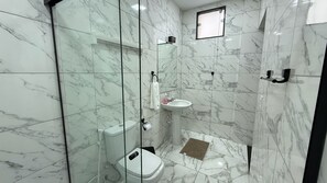 A bathroom with a toilet, sink, and shower area, all with marble flooring and walls. - Suite 3 in Arraial do Cabo on Praia Grande, 2 minutes from the sand. (Arraial do Cabo)