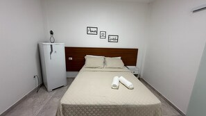 A hotel room with a bed, a nightstand, a small white cabinet, and a wall with three framed words. - Suite 3 in Arraial do Cabo on Praia Grande, 2 minutes from the sand. (Arraial do Cabo)