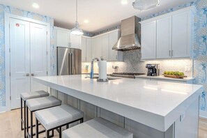 A modern kitchen with a large island, stainless steel appliances, and a herringbone-patterned backsplash. - Luxury Dunes Paradise - Private Pool (Hilton Head Island)