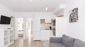 A modern apartment with a kitchen, living room, and a hallway leading to a bedroom. - Nuria Cala Blanca (Cala Blanca)
