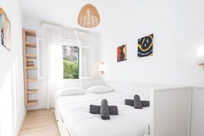 Una camera da letto con un letto, una finestra, uno scaffale e opere d'arte alle pareti.
