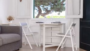 A modern living room with a gray sofa, a white dining table, and two white chairs. - Nuria Cala Blanca (Cala Blanca)