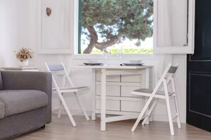 A modern living room with a gray sofa, a white dining table, and two white chairs. - Nuria Cala Blanca (Cala Blanca)