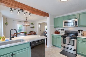 A kitchen with teal cabinets, a central island, a dishwasher, a stove, and a microwave.
