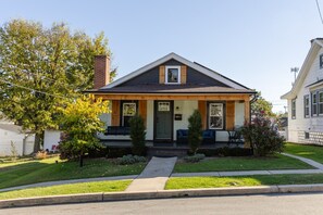 A two-story house with a front porch, a chimney, and a well-maintained lawn.