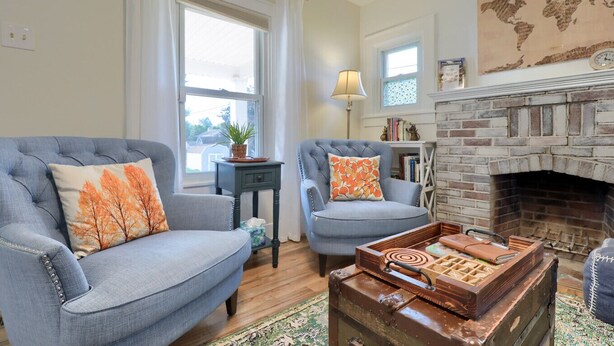 Un salon avec deux fauteuils, une petite table, une cheminée et une carte du monde accrochée au mur.