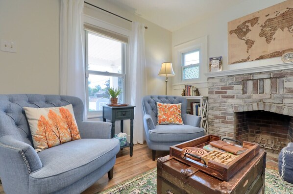 A living room with two armchairs, a small table, a fireplace, and a world map on the wall.