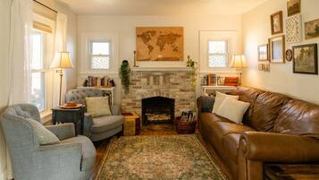 A cozy living room with a fireplace, two armchairs, a sofa, and a patterned rug.