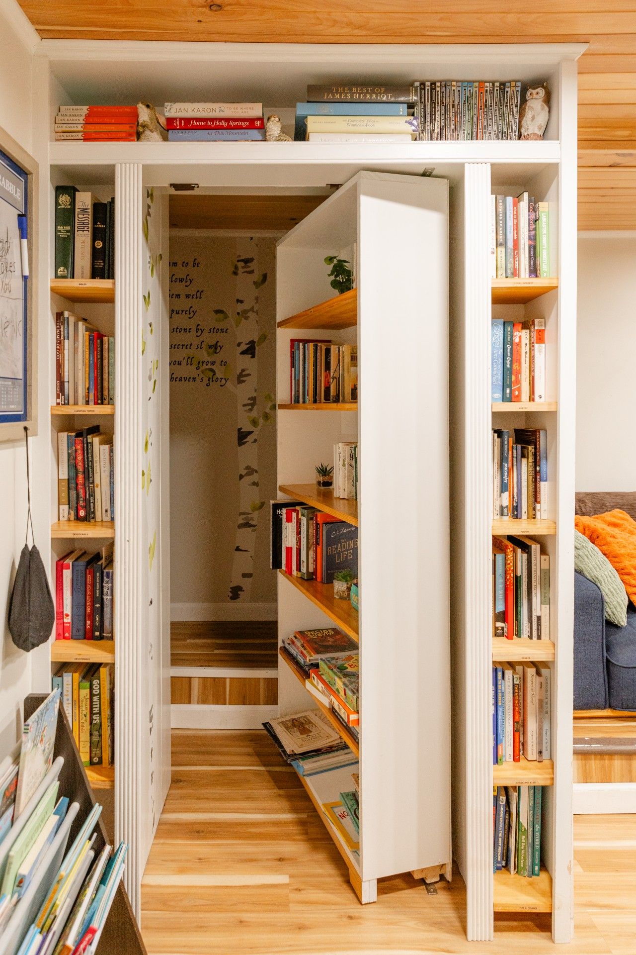 A compact, multi-level bookshelf with a variety of books and decorative items, including a small owl figurine.