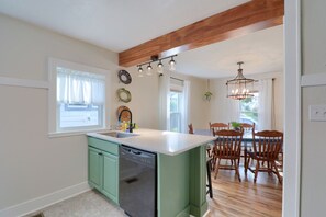 A kitchen with a green island, a dining area with wooden chairs, and a hanging light fixture. - The Storybook Cottage | Close to Lancaster | Secret Room (Lancaster)