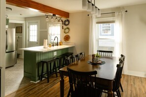A modern kitchen with a central island, wooden dining table, and chairs.
