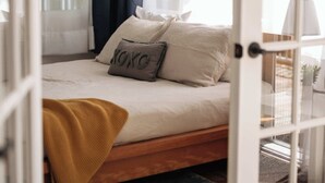Ein Schlafzimmer mit einem Bett, einem Fenster mit Vorhängen und einer Tür.