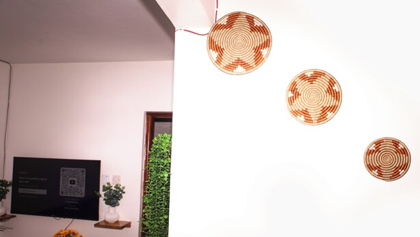 A room with a television, a small table with a vase of flowers, and three circular wall decorations. - AJ Urban Escape (Nairobi)